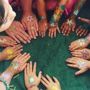 A group of children with painted hands in a circle.