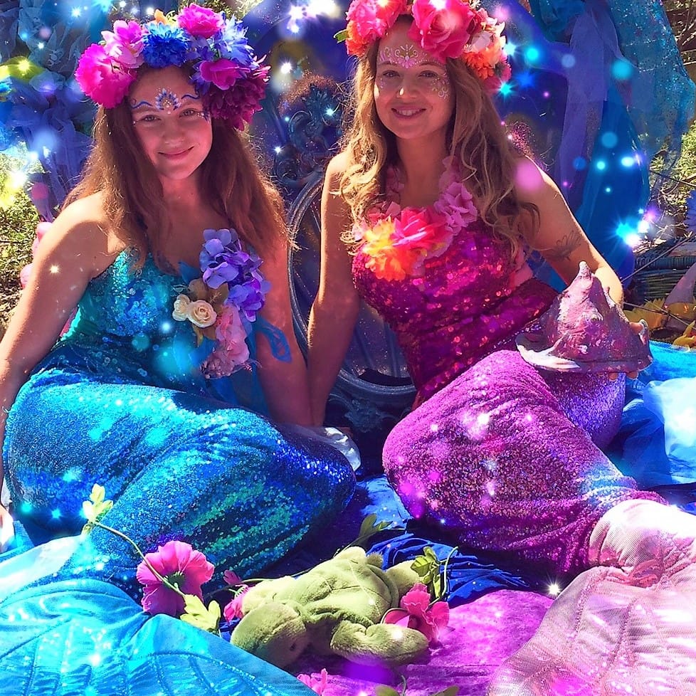 Made with Repix (http://repix.it) Two women dressed as mermaids sitting on a blanket.