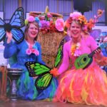Story Telling Square Two women dressed in colorful costumes and holding guitars.
