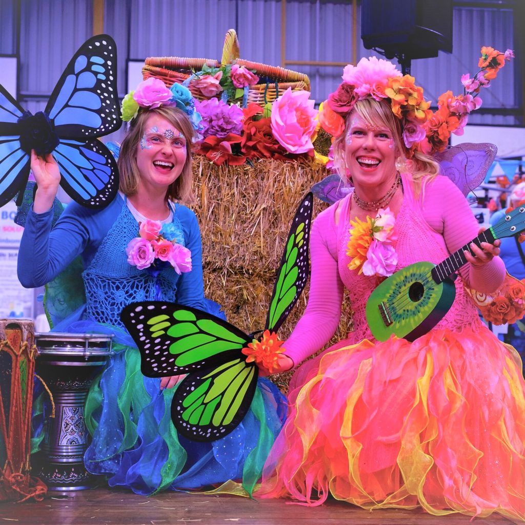 Story Telling Square Two women dressed in colorful costumes and holding guitars.