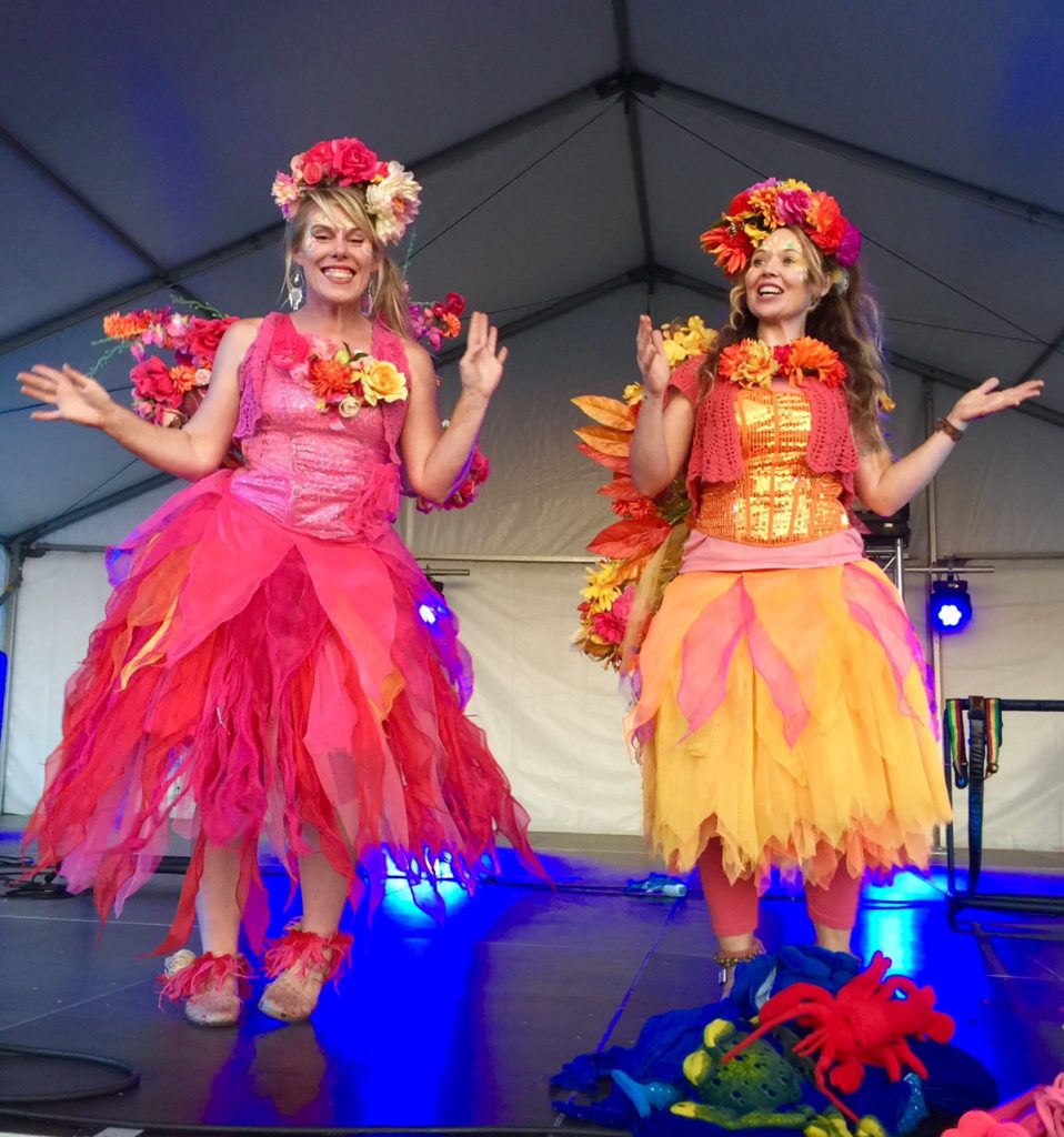Fairy Stage Show Two women wearing colorful clothing on a stage.