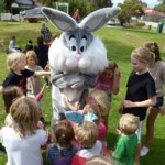 A group of kids around a person in a bunny garment.