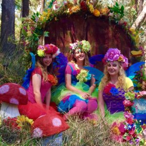 Three women dressed up as fairy posing in the woods.