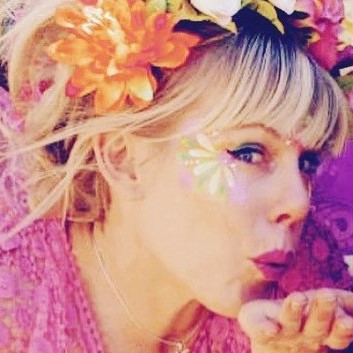 Make a wish with a fairy square Woman with a floral headband blowing a kiss, featuring a butterfly face sticker, against a purple background.
