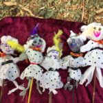 A group of dolls with feathers on sticks.