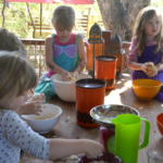 A group of children are sitting at a table making food.